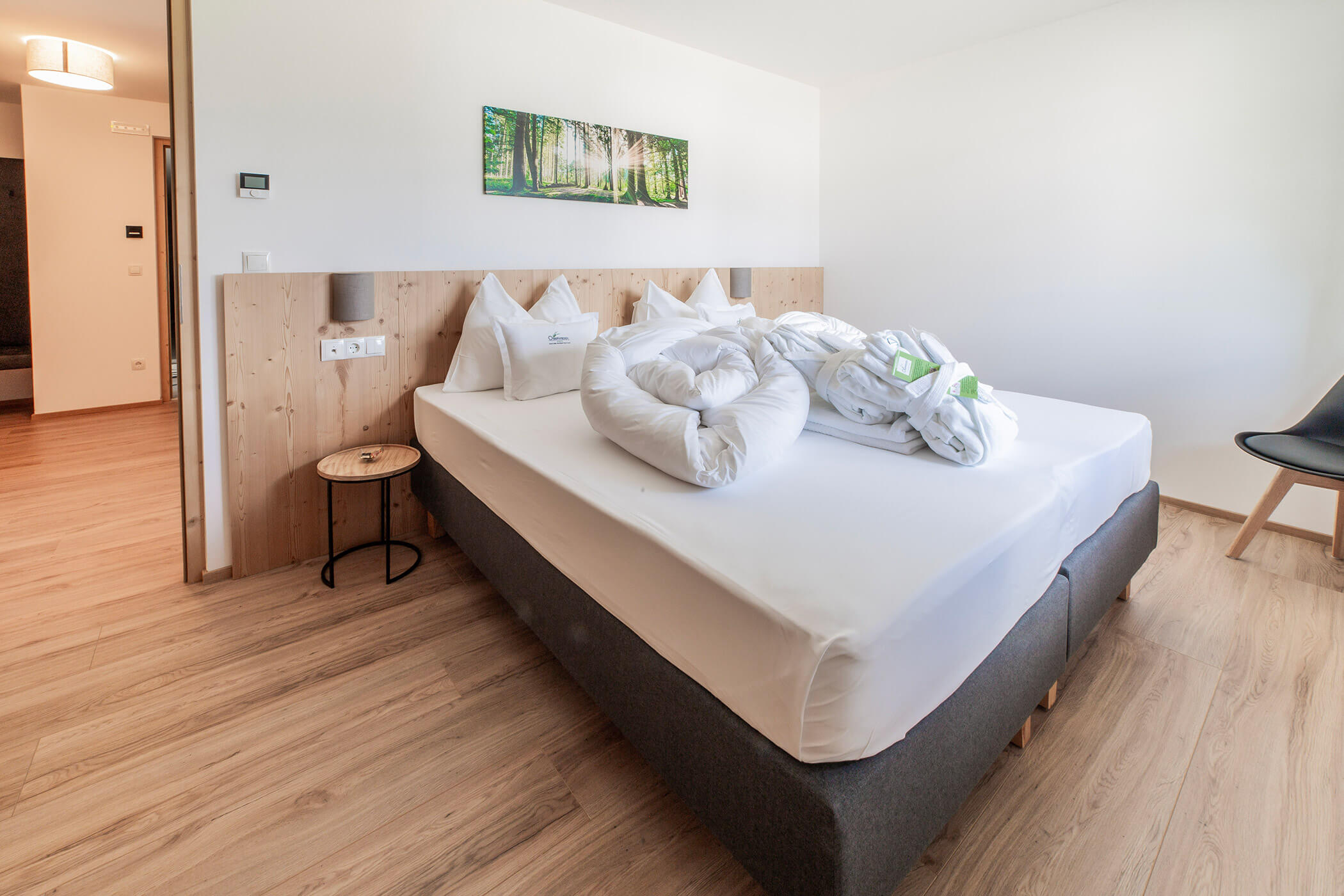 Camera da letto luminosa con letto matrimoniale già rifatto, asciugamani piegati a forma di cigni e arredi moderni in legno. - Hotel Oberwiesen