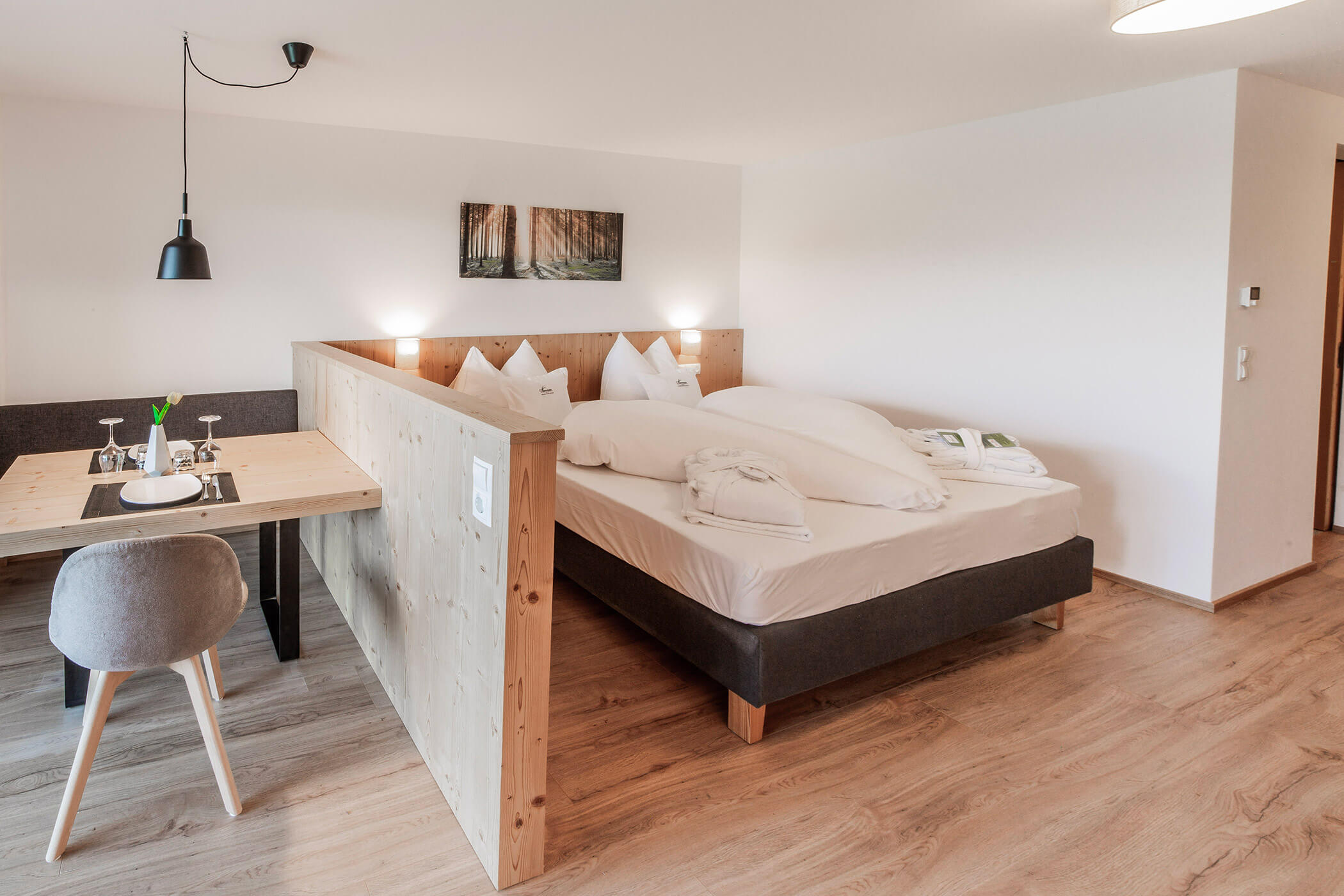 Moderna camera d'albergo con letto matrimoniale, tavolo da pranzo, sedia grigia e pavimenti in legno. - Hotel Oberwiesen