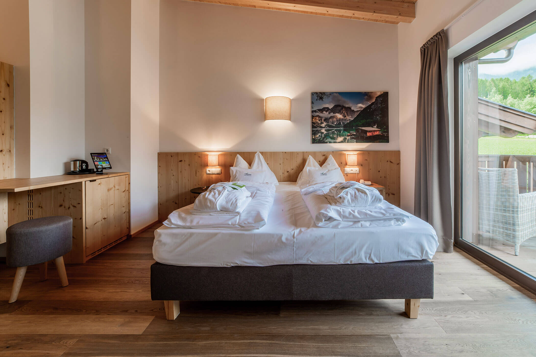 Moderna camera d'albergo con letto matrimoniale, accappatoi, scrivania e ampia finestra con vista sull'esterno. - Hotel Oberwiesen