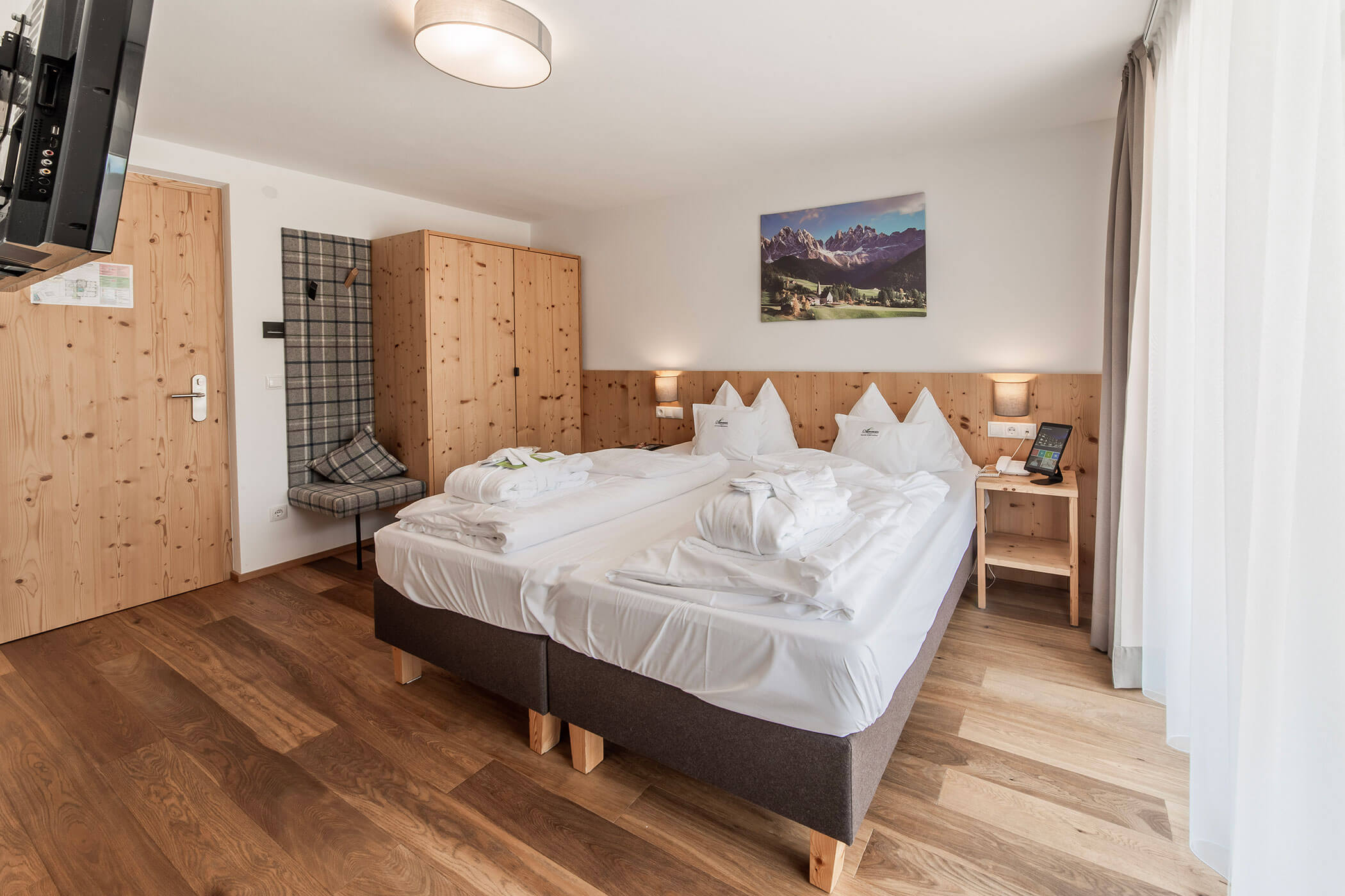 Camera d'albergo luminosa con due letti singoli, mobili in legno, una grande finestra e un quadro con una montagna appeso alla parete. - Hotel Oberwiesen