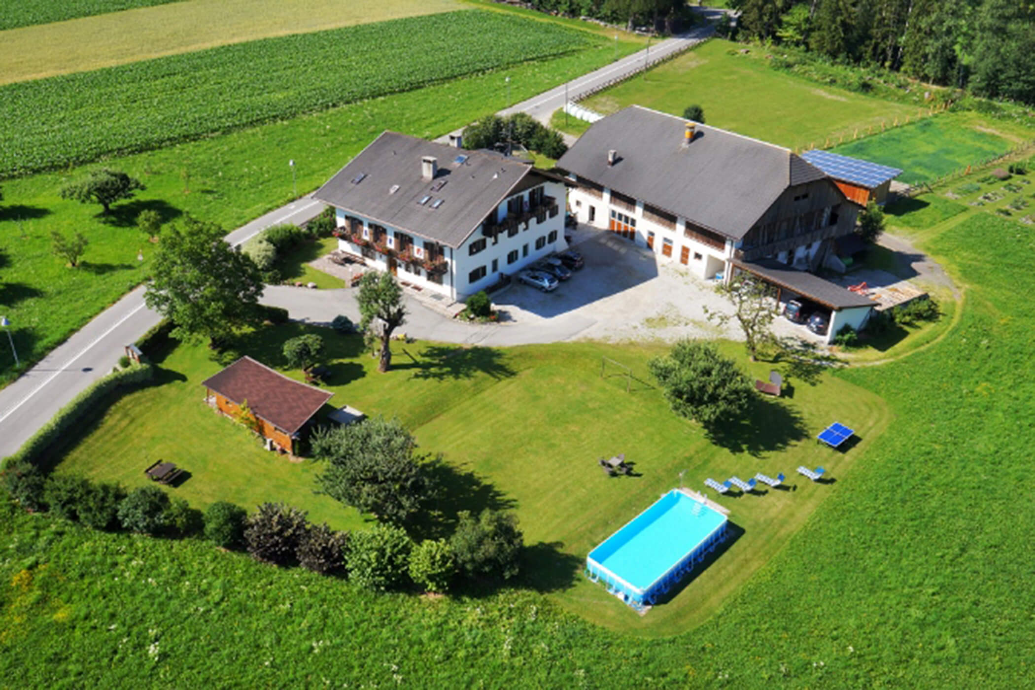 Luftaufnahme eines Bauernhauses mit Pool, Liegestühlen und Gärten, umgeben von Feldern und Bäumen. - Hotel Oberwiesen