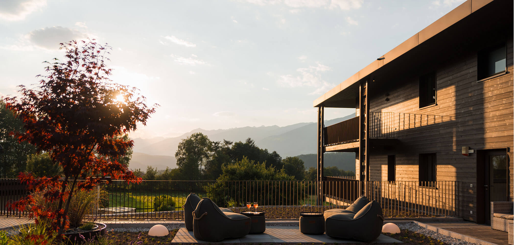 Modernes Haus mit Terrasse, Liegestühlen, Bergblick und Sonnenuntergang in einer ruhigen Umgebung im Freien. - Hotel Oberwiesen