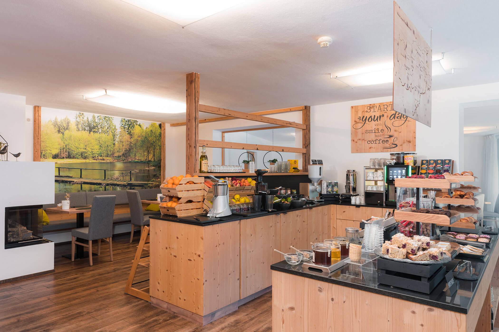 Colazione a buffet in una sala accogliente con prodotti da forno, frutta, succhi di frutta e macchine per il caffè disposte sui banconi in legno. - Hotel Oberwiesen