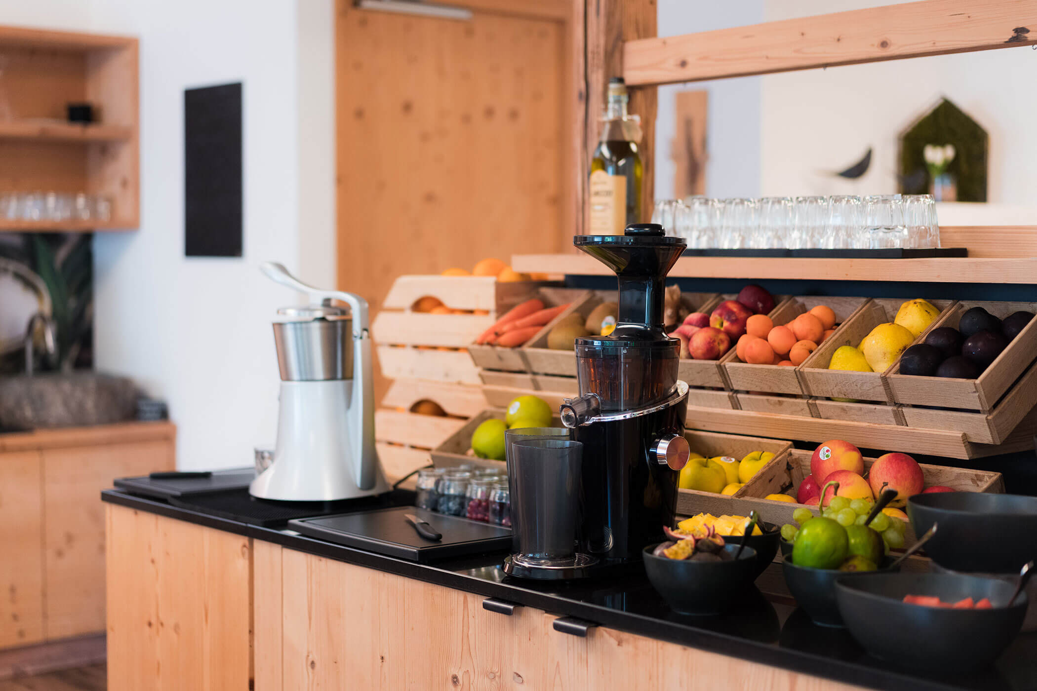 Bancone in legno con frutta fresca, macchine per succhi e bicchieri disposti in modo da consentire la preparazione dei succhi in autoservizio. - Hotel Oberwiesen
