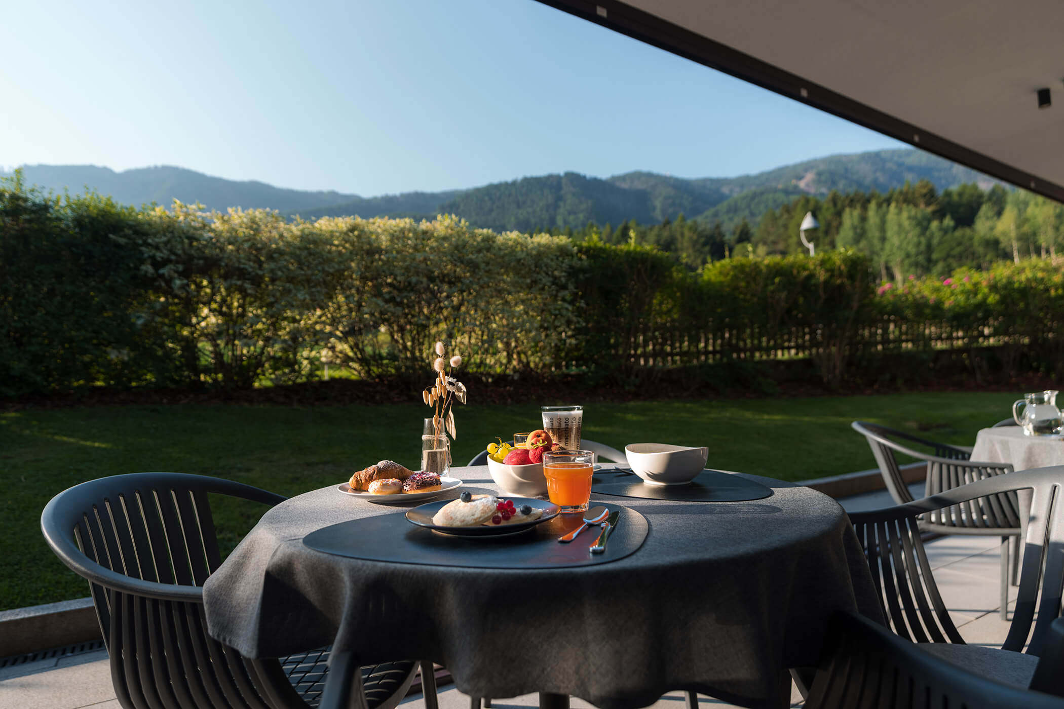 Breakfast is set on a patio table with a mountain view and green landscape in the background. - Hotel Oberwiesen