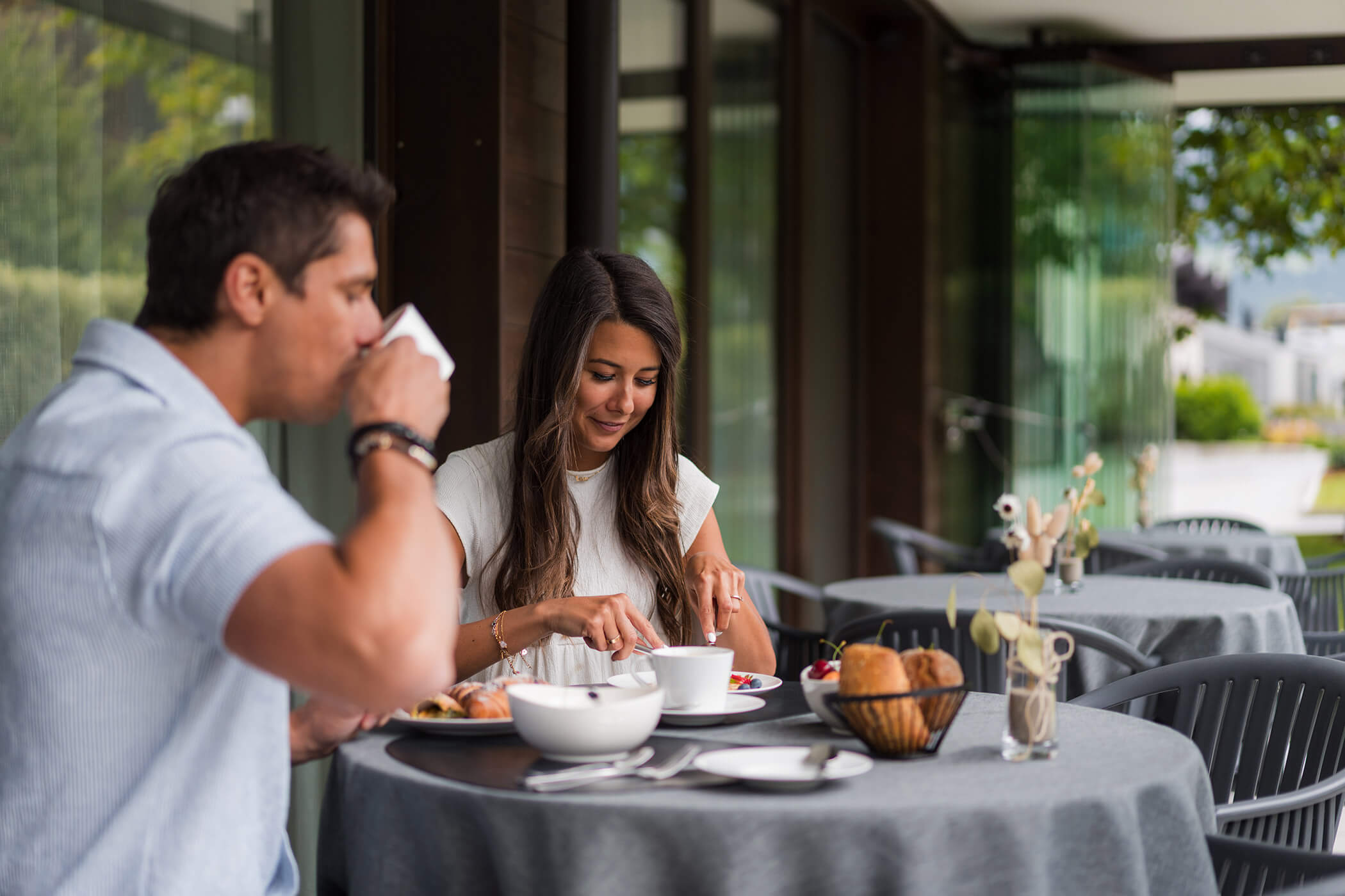 A man and woman enjoy breakfast together at an outdoor cafe with gray tablecloths. - Hotel Oberwiesen