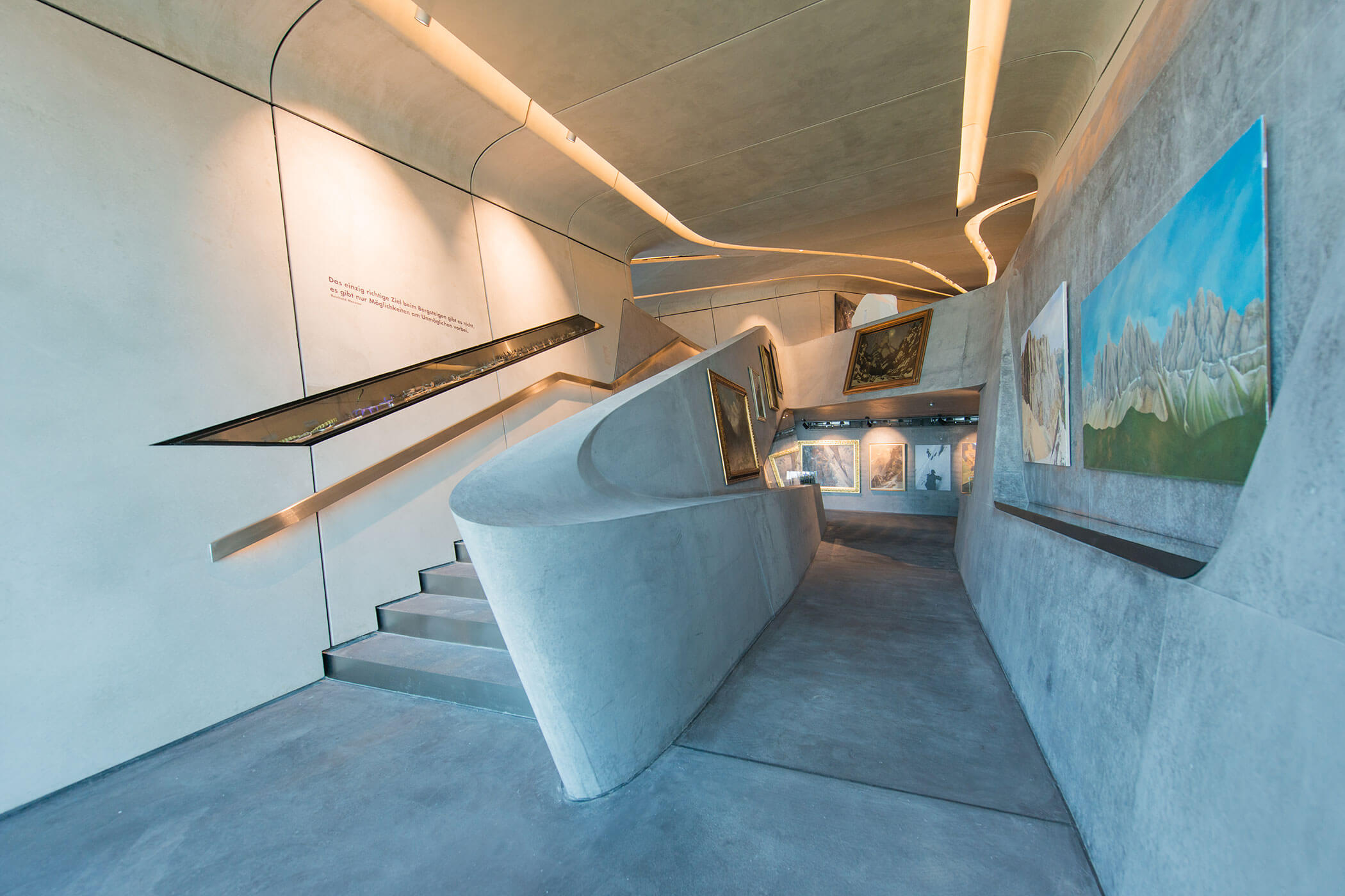 Galleria d'arte moderna con pareti curve in cemento e una rampa, in cui i dipinti sono esposti lungo il percorso. - Hotel Oberwiesen