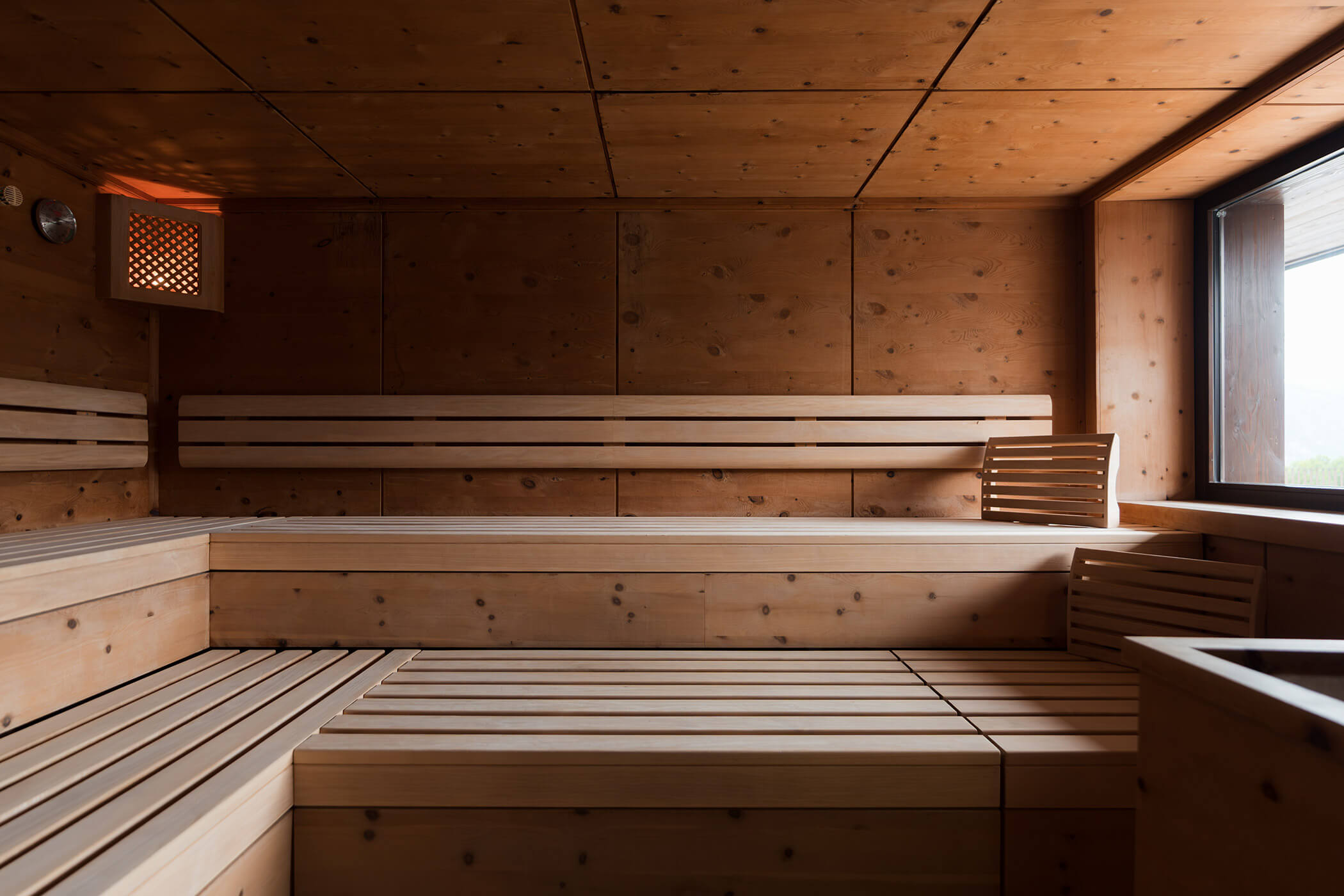 Eine leere Holzsauna mit Bänken, einem kleinen Fenster und warmem, natürlichem Licht. - Hotel Oberwiesen