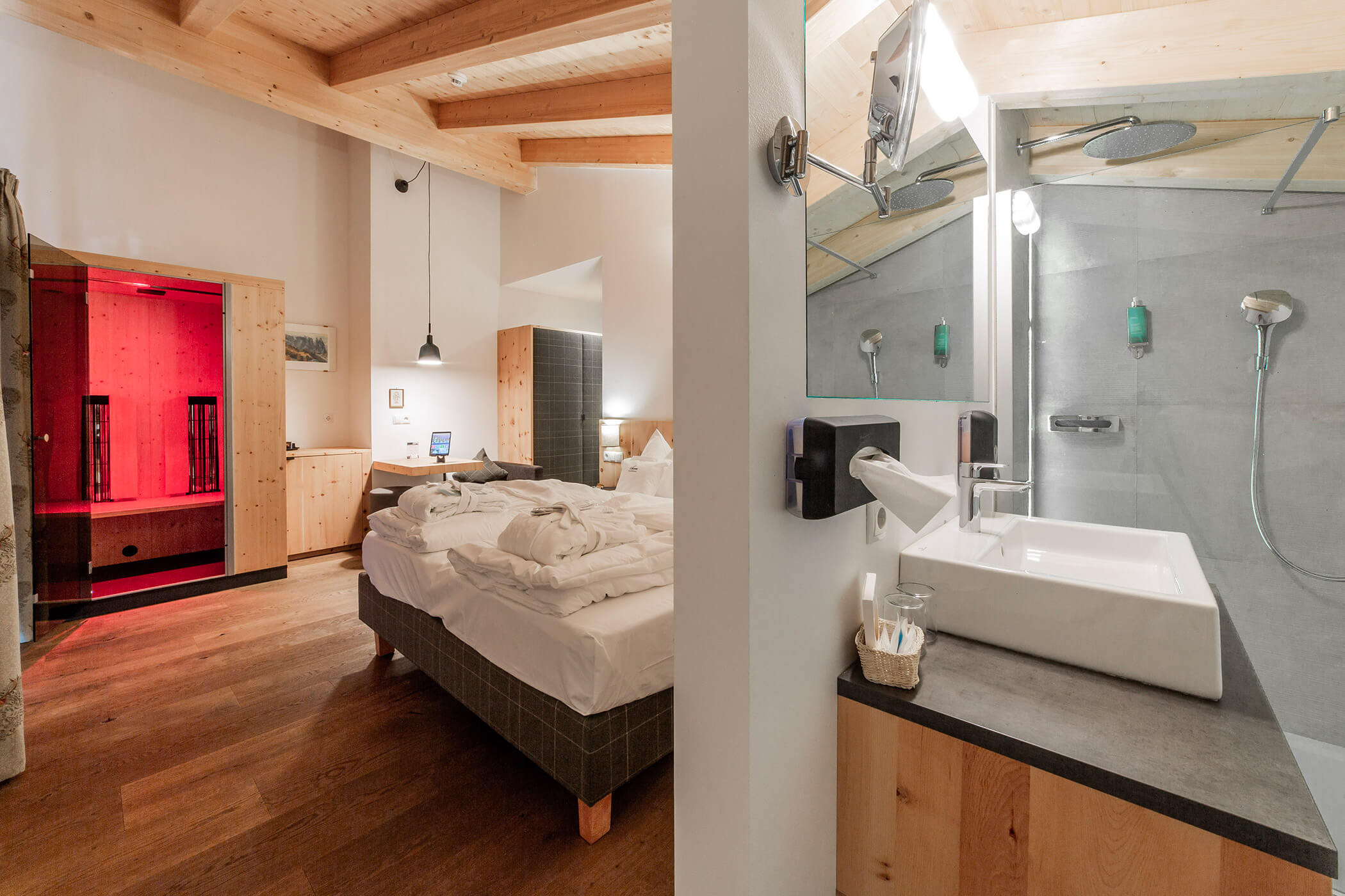 Moderna camera d'albergo con letto matrimoniale, accappatoi e bagno a vista dotato di lavabo e doccia a effetto pioggia. - Hotel Oberwiesen